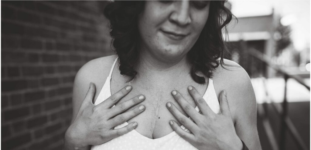 Black and white Image on woman with hands on her chest.