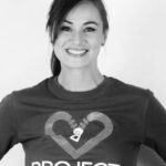 Black and white image of woman smiling with Project Heart shirt on.