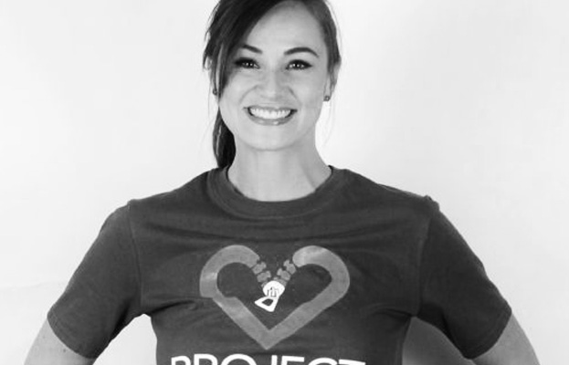 Black and white image of woman smiling with Project Heart shirt on.