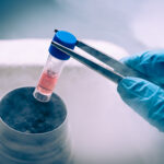 Scientist picking up a test tube with tweezers